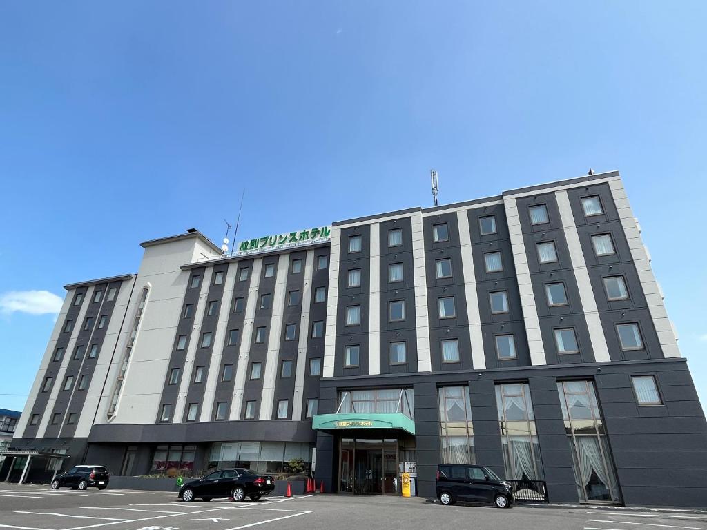 a large building with cars parked in a parking lot at Monbetsu Prince Hotel in Mombetsu