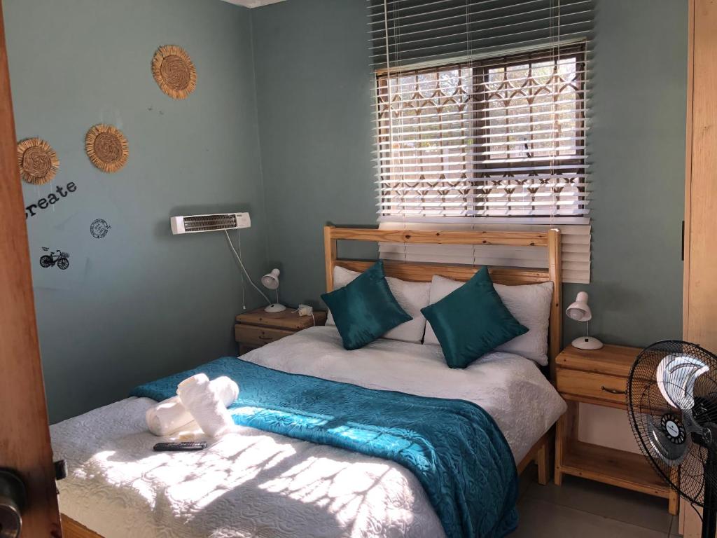 a bedroom with a bed with a blue blanket and a window at Pozi Guest House in Sasolburg