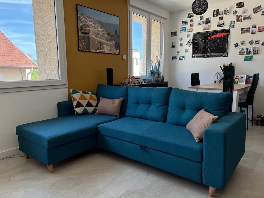 un sofá azul sentado en una sala de estar en Lumineux, centre-ville d’Oyonnax, à 2 pas des lacs, en Oyonnax