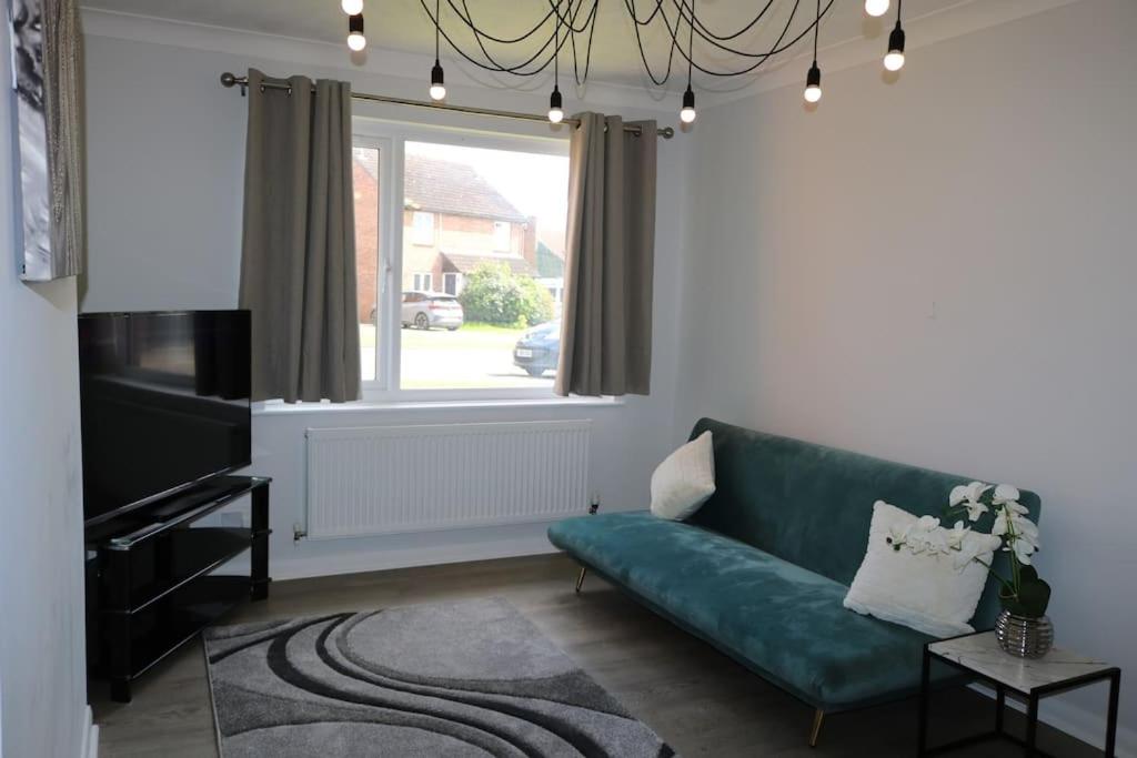 a living room with a green couch and a window at Lovely flat with Wi-Fi and free parking in Reading