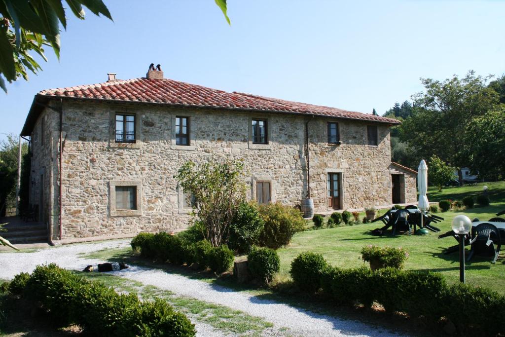une maison en pierre avec un jardin en face dans l'établissement Antico Casale Pozzuolo, à Seggiano