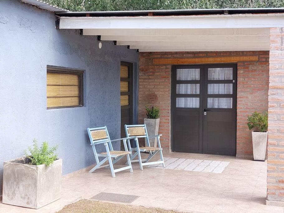 dos sillas sentadas en un porche con una puerta en Cardozo House, casa de campo en Villa Dolores