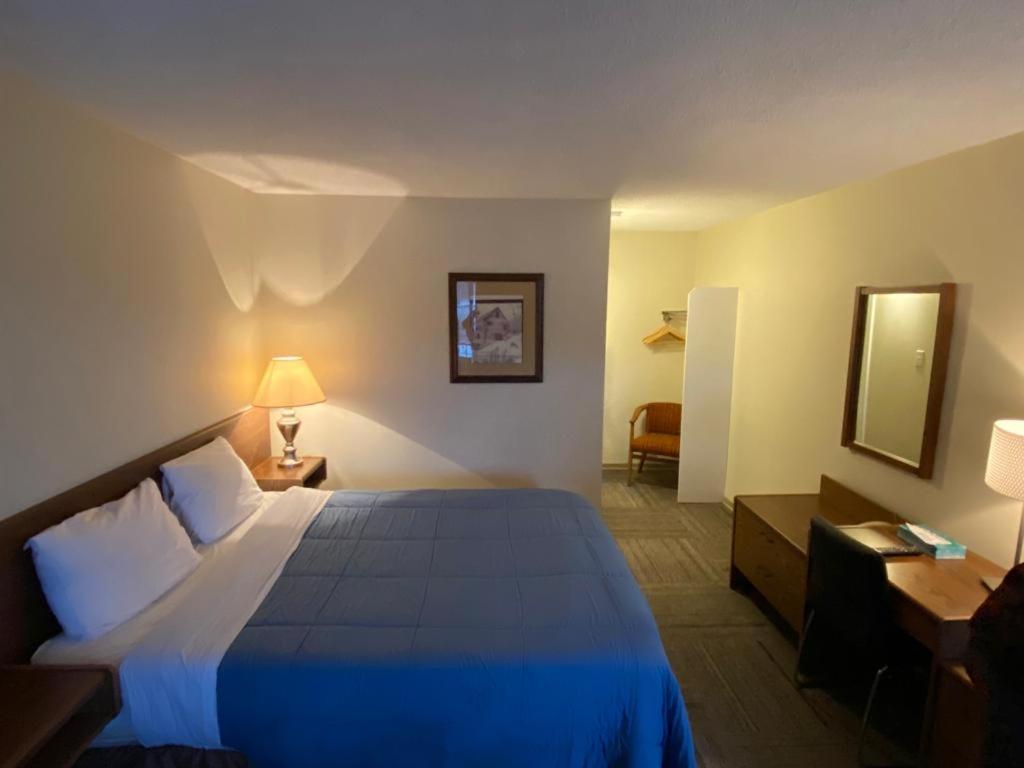 a hotel room with a bed with a blue blanket at Houston Motor Inn in Houston