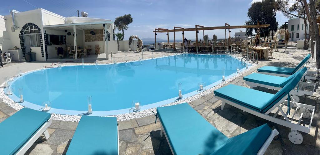 une grande piscine bleue avec des chaises bleues dans l'établissement Dawn Suites Santorini, à Vourvoúlos