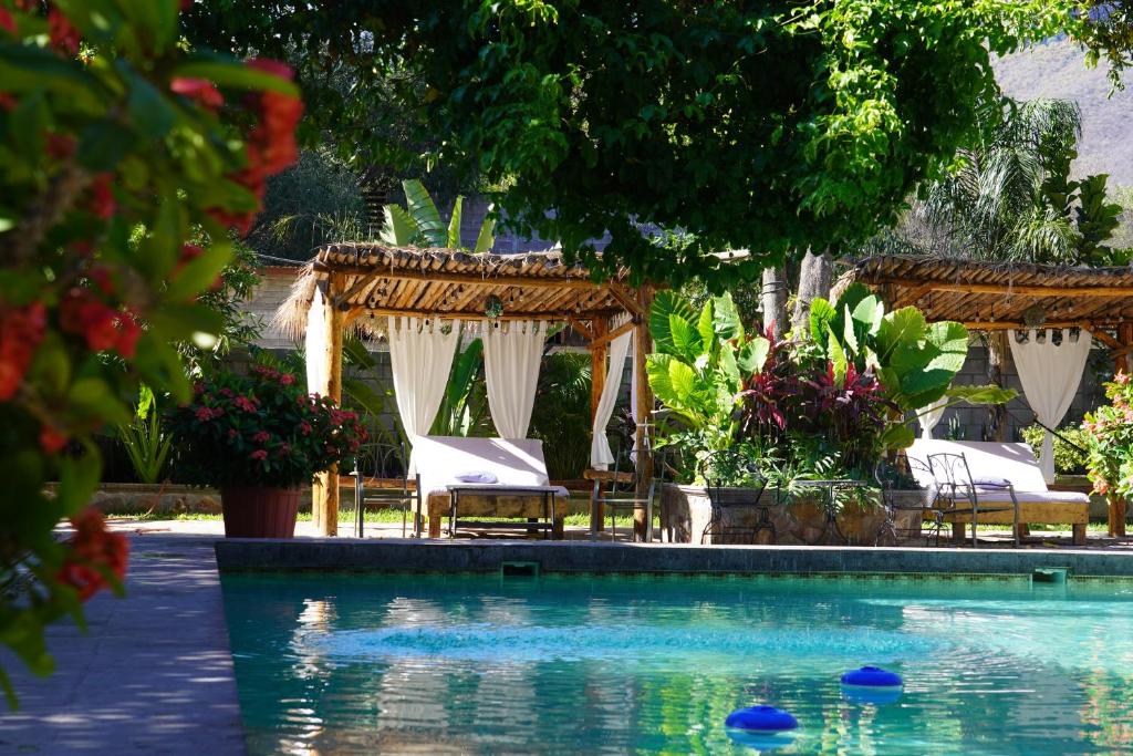 uma piscina com cadeiras e guarda-sóis ao lado de um resort em Hotel Villa de Urike em Urique