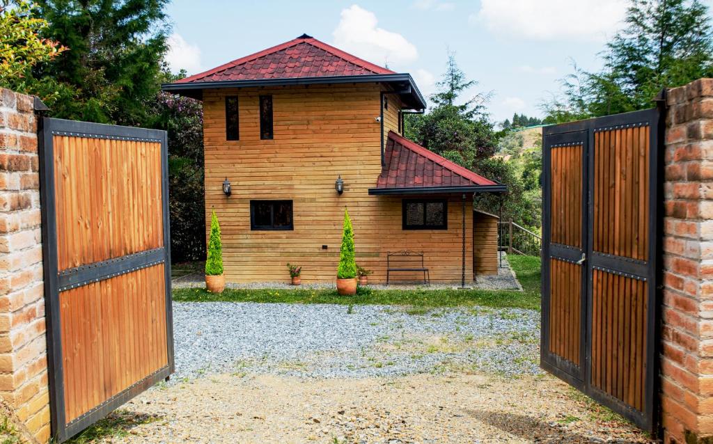 a wooden gate leading to a house with a building at Mia`s cabañas in Rionegro