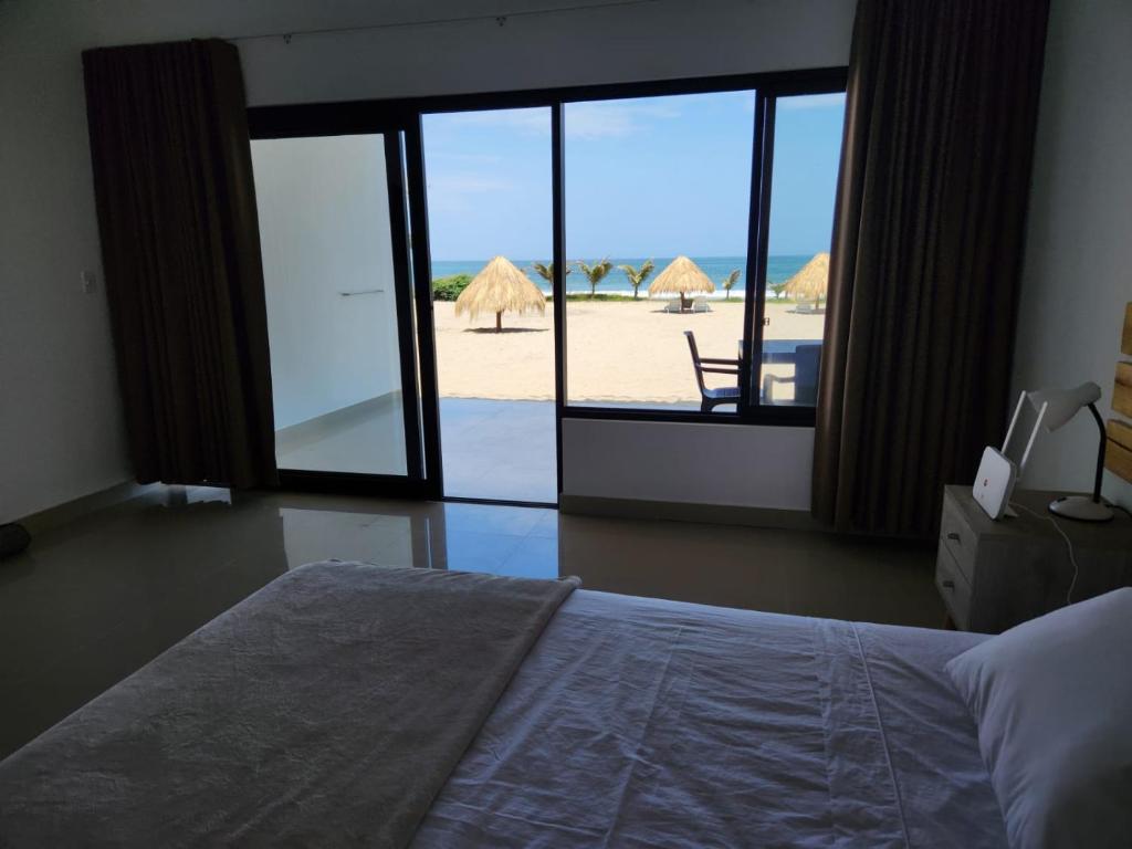 a bedroom with a bed and a view of the beach at Las Hamacas in Canoas De Punta Sal