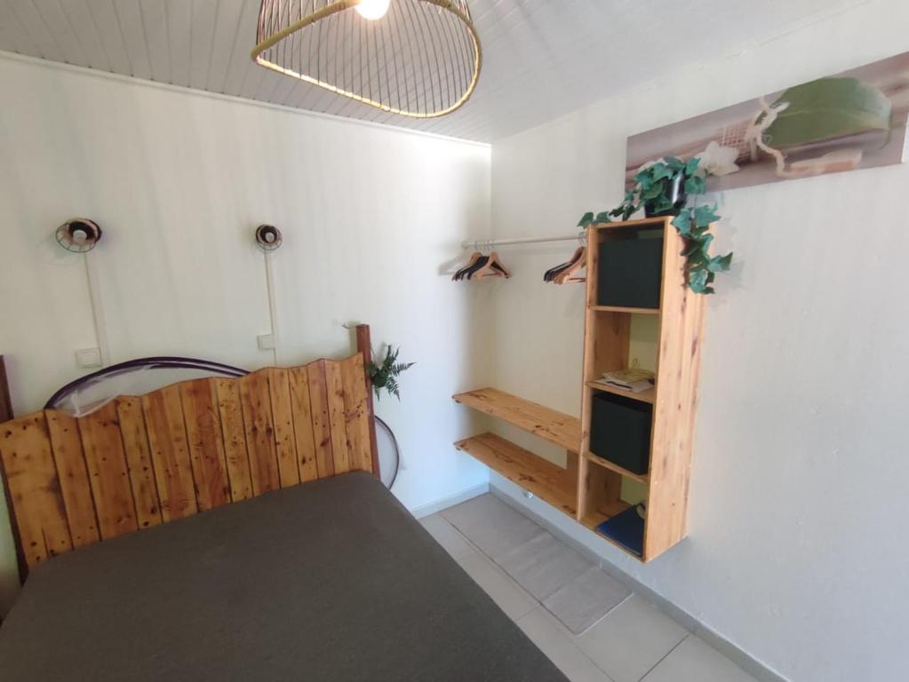 een kamer met een houten bed en een plank bij Le Moubin in La Trinité