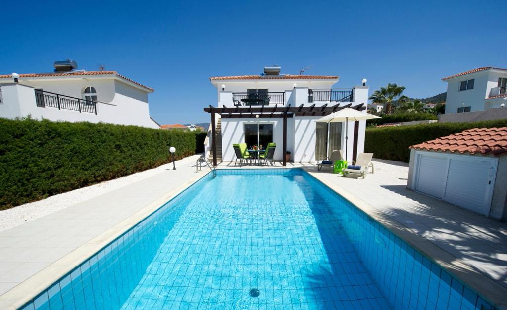 - une piscine en face d'une maison dans l'établissement Sandy Coast Villas Anemone, à Argaka