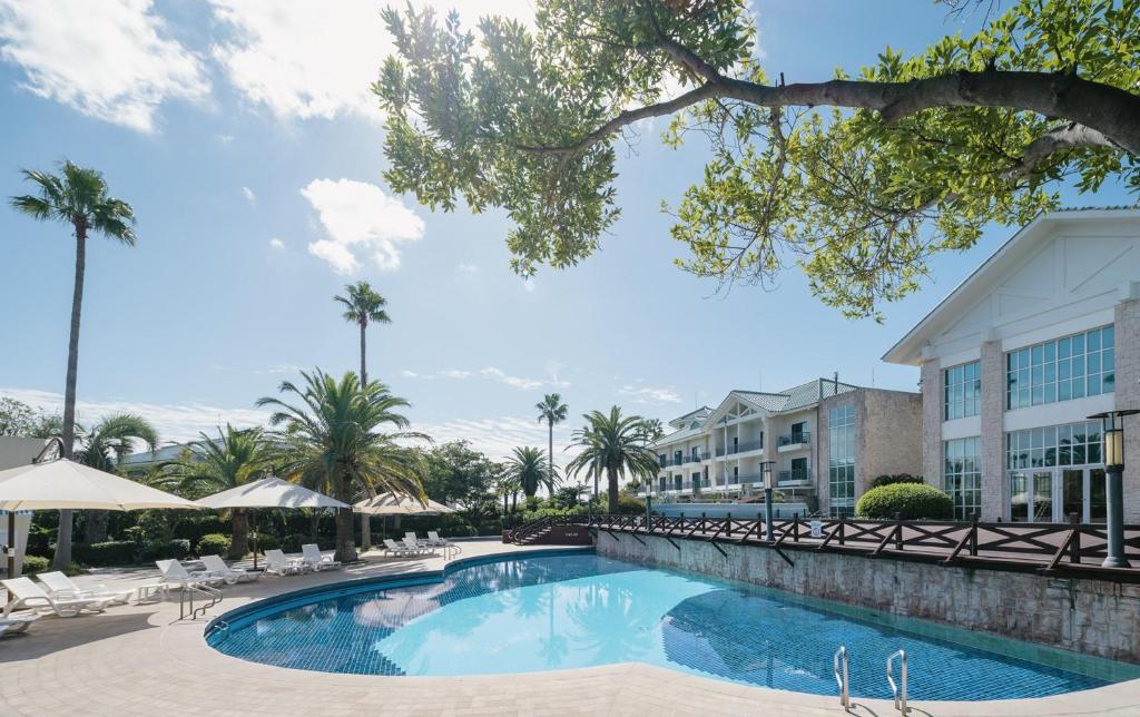 a pool at a resort with chairs and umbrellas at Bloom Hotel in Seogwipo