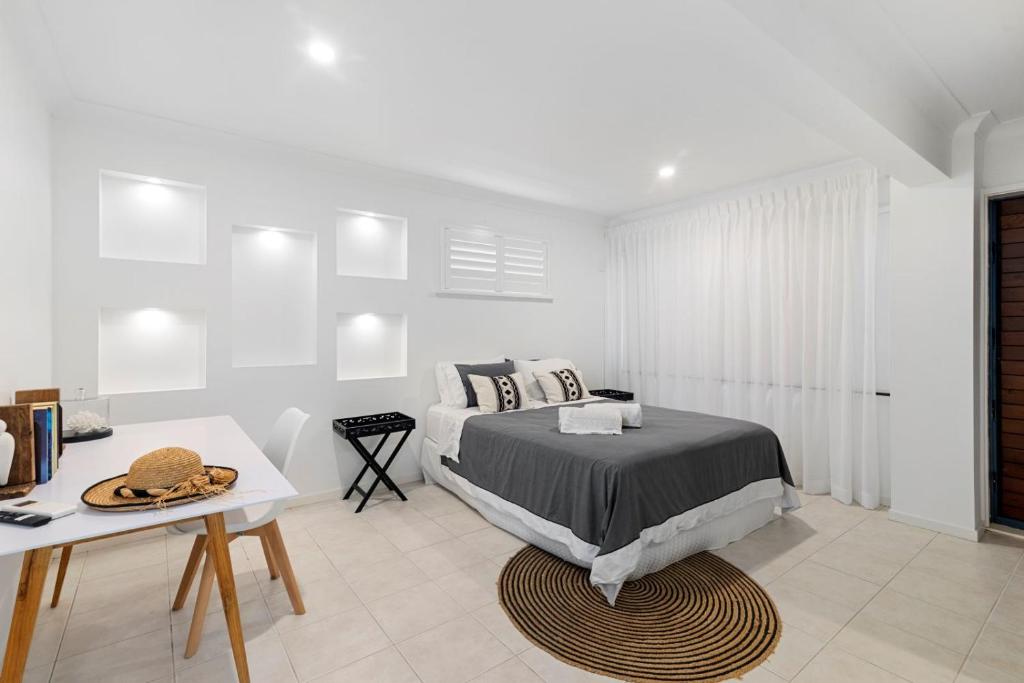 a bedroom with a bed and a table and a desk at Castaway in Tugun in Gold Coast