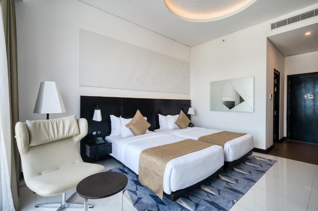 um quarto de hotel com uma cama grande e uma cadeira em Orion City Hotel em Colombo