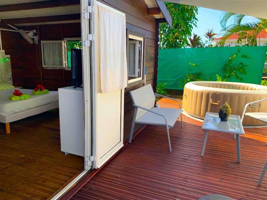 une terrasse avec une baignoire, une chaise et une télévision dans l'établissement Bungalow Ti Kako, à Capesterre-Belle-Eau