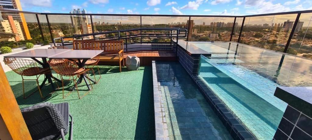 a balcony with a table and a pool on a building at Reserva Madero Requinte Apto 104 in Natal