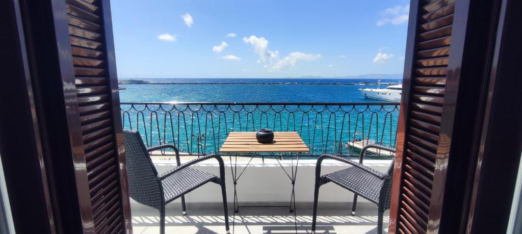 balcón con mesa, sillas y vistas al océano en Flisvos Apartments en Tinos Town