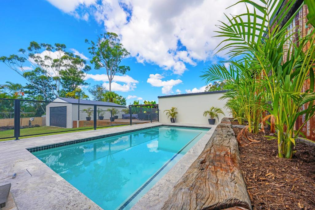 a swimming pool in the backyard of a house with palm trees at Pet Friendly Family Home with Pool Close to Theme Parks in Gold Coast