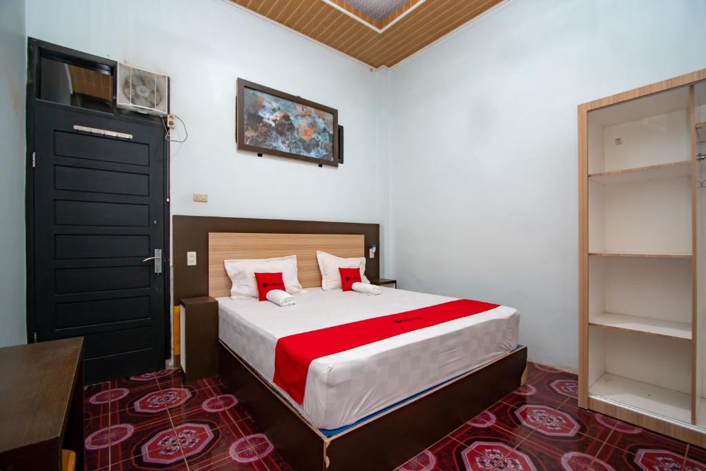 1 dormitorio con 1 cama grande con sábanas rojas y blancas en RedDoorz Syariah near Danau Lut Tawar Takengon, en Takengon