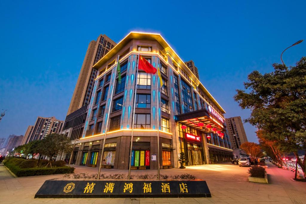 um edifício alto com um sinal em frente em Hilmanhomeful Hotel - Caijia Subway Station em Chongqing