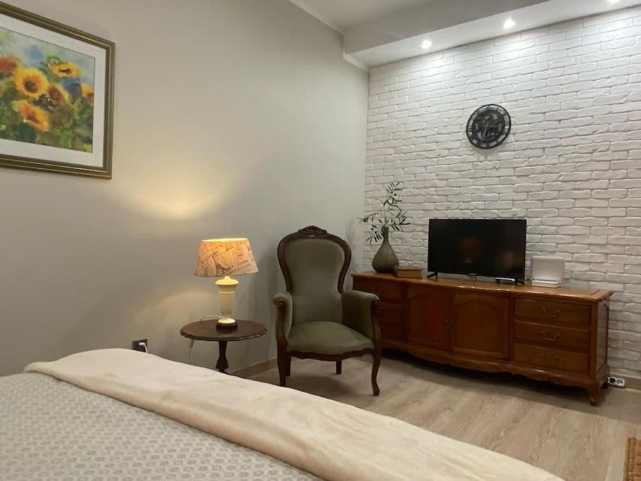 a bedroom with a bed and a chair and a tv at Przytulne w Centrum in Ostrowiec Świętokrzyski