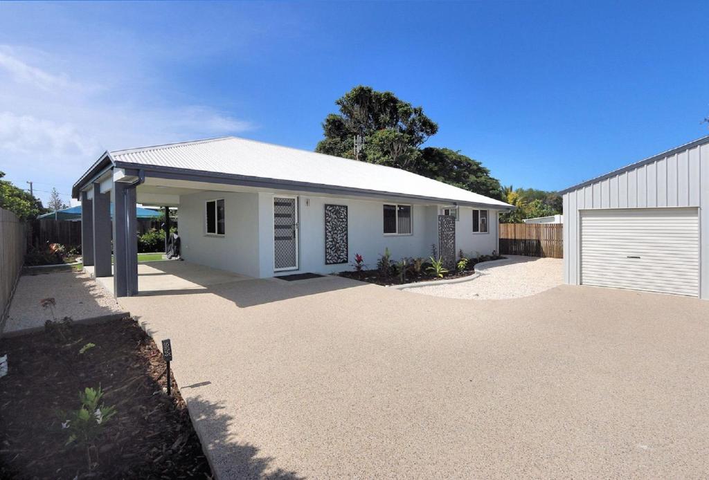 a white house with a garage and a driveway at Tanner St Retreat in Bargara