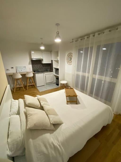Cette chambre comprend un grand lit blanc et une cuisine. dans l'établissement Studio Cosy à 10 min de Paris, à Deuil-la-Barre