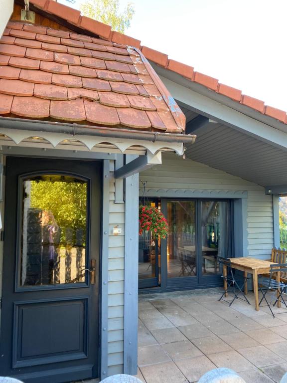 a house with a blue door and a table on a patio at Maison chaleureuse - Gérardmer in Gérardmer