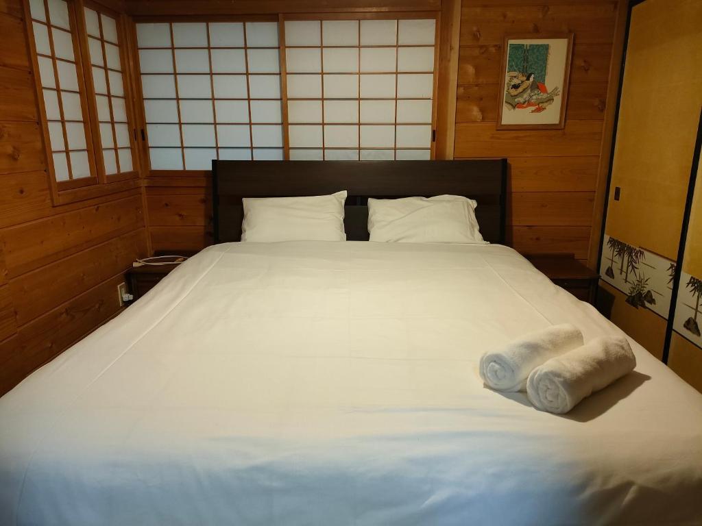 a bed in a room with two rolled towels on it at Hakuba Matata Apartment in Hakuba