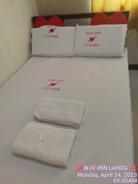 Una cama con toallas blancas encima. en WJV INN LAHUG, en Tabok