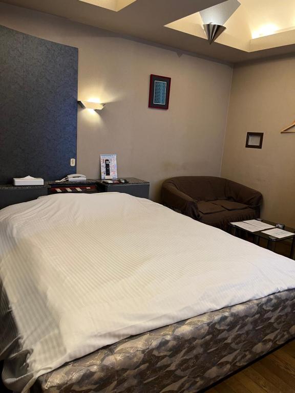 um quarto com uma grande cama branca e um sofá em HOTEL　TRITON em Itoman