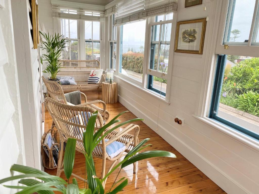 a room with two chairs and a table and windows at Cosy coastal cottage- Allwood Harbour in Kiama