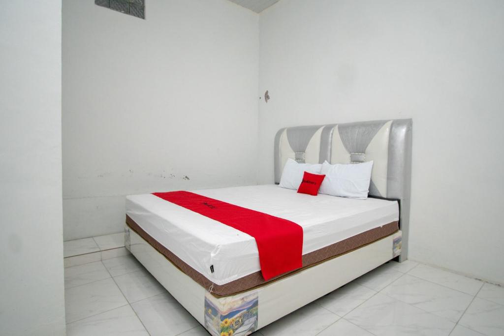 a bed in a white room with a red blanket on it at RedDoorz Syariah near Danau Lut Tawar Takengon 2 in Takengon