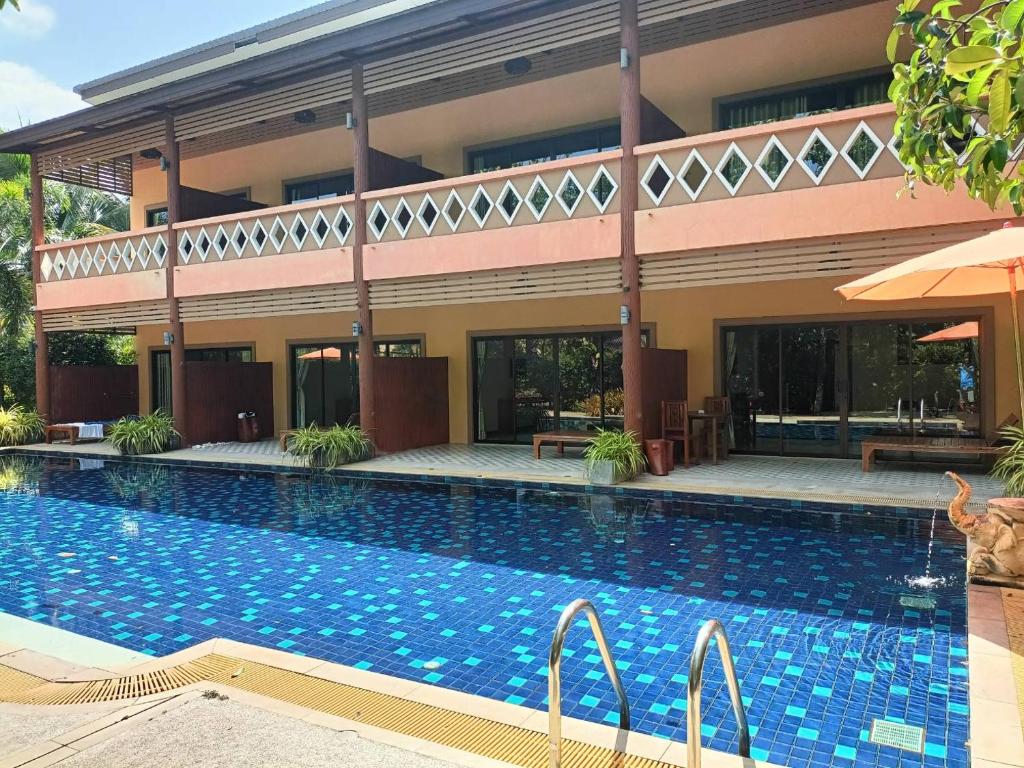 a swimming pool in front of a building at Baan Suan Villas Resort in Ban Suan