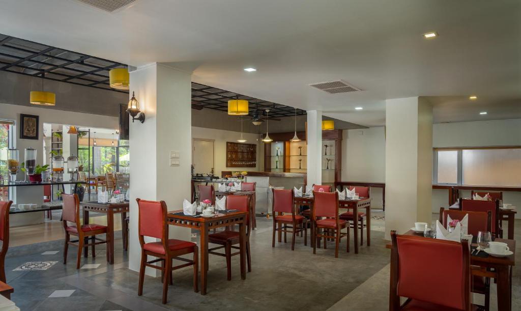 a restaurant with wooden tables and red chairs at Sala Siem Reap Hotel in Siem Reap