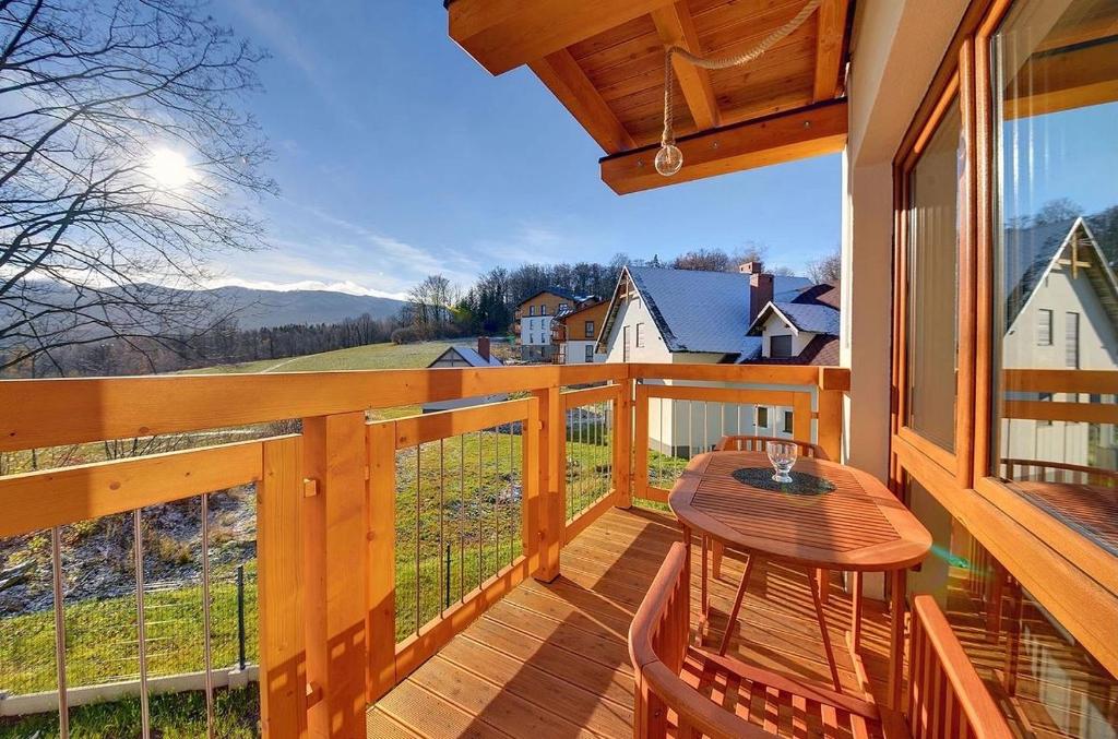 a wooden balcony with a table and chairs on it at Apartamenty Sun Seasons 24 - Złoty Widok in Szklarska Poręba