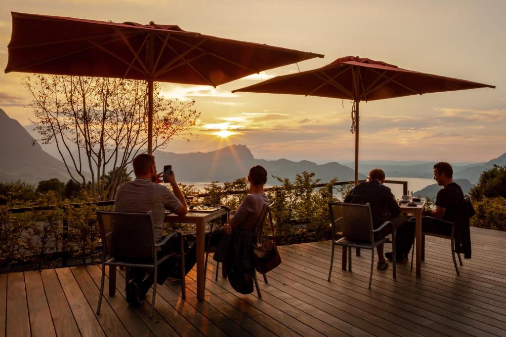 um grupo de pessoas sentadas numa mesa sob guarda-chuvas em Seeblick Höhenhotel em Emmetten