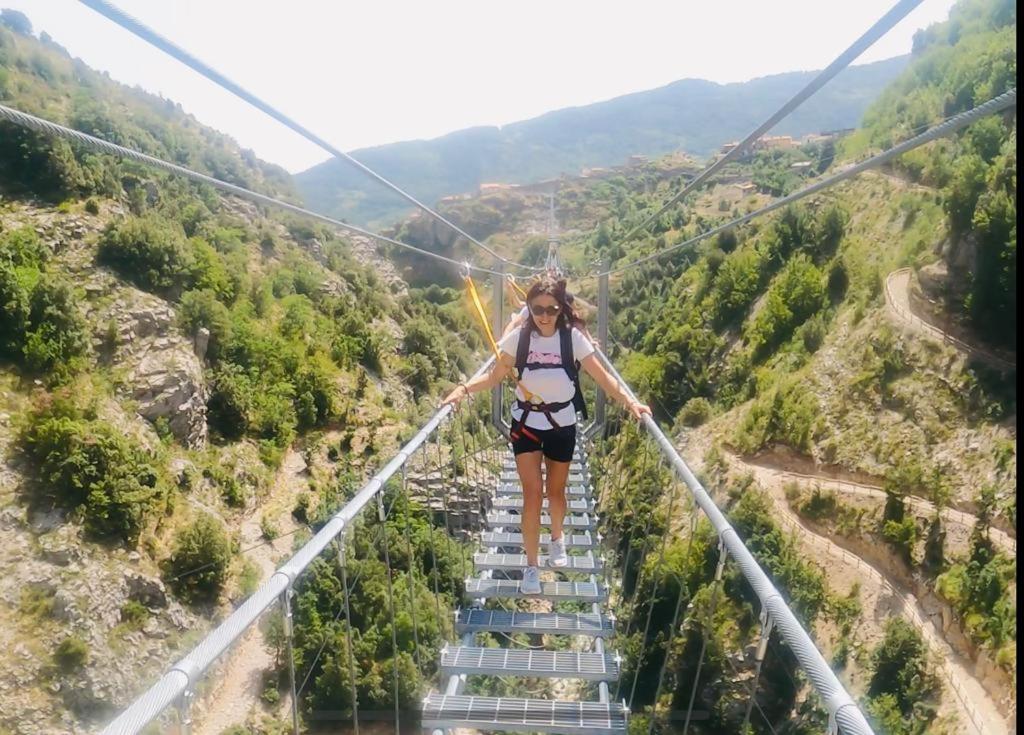 une femme marchant sur un pont suspendu au-dessus d'une montagne dans l'établissement TibetiAmo, à Castelsaraceno