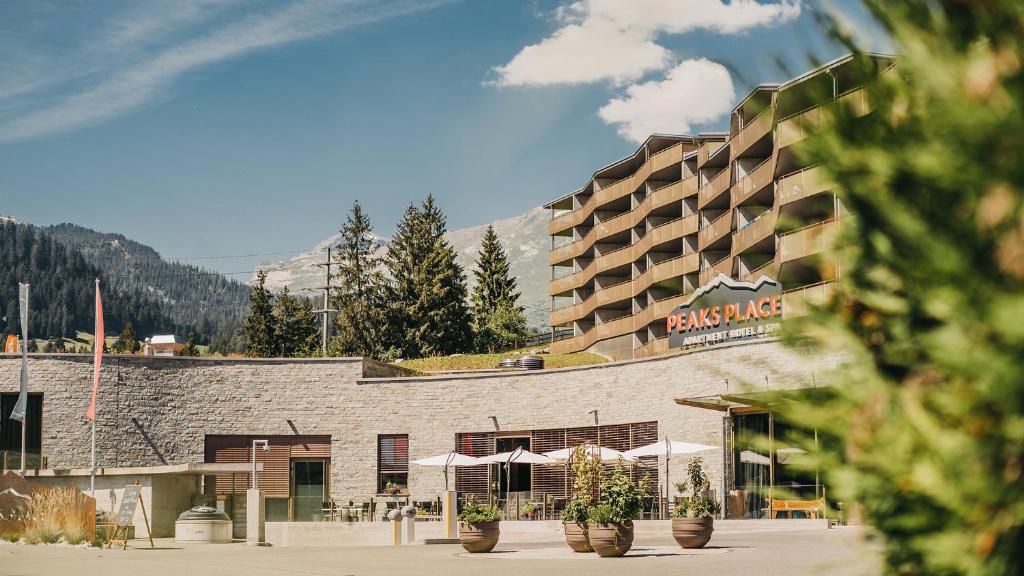 a hotel with potted plants in front of a building at Peaks Place Apartments & SPA in Laax