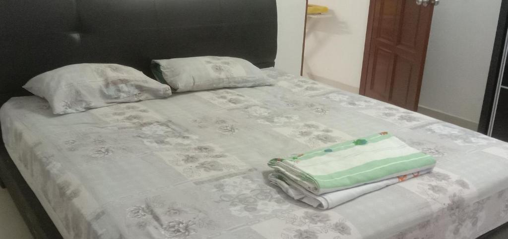 a bed with a suitcase sitting on top of it at Homestay Humair in Marang