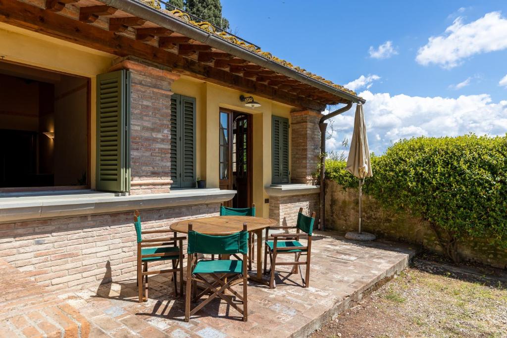a patio with a table and chairs and an umbrella at Fattoria la Gigliola - La Limonaia in Montespertoli