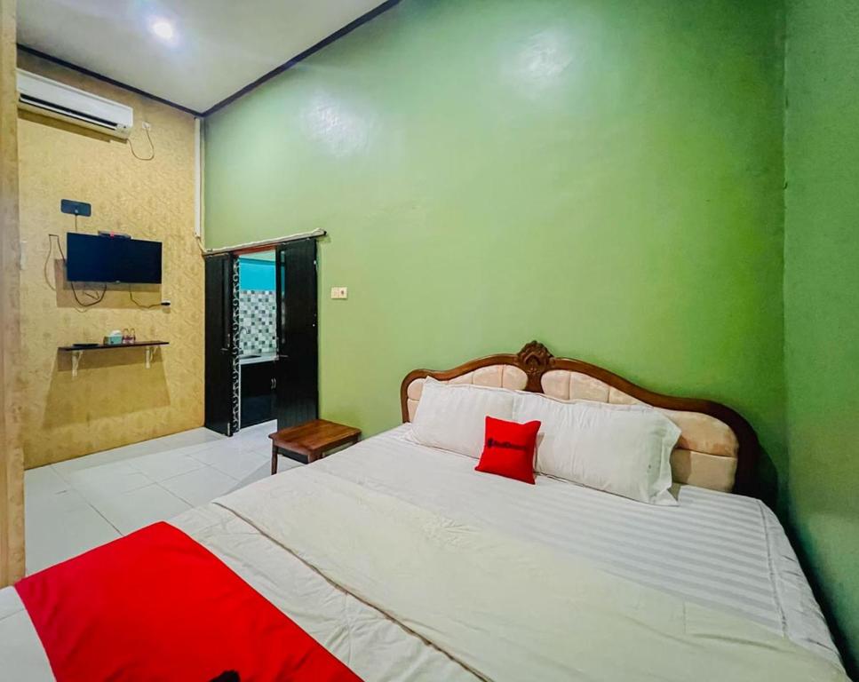 a bedroom with a white bed with a red pillow at RedDoorz Syariah near Sunrise Mall Mojokerto in Mojokerto