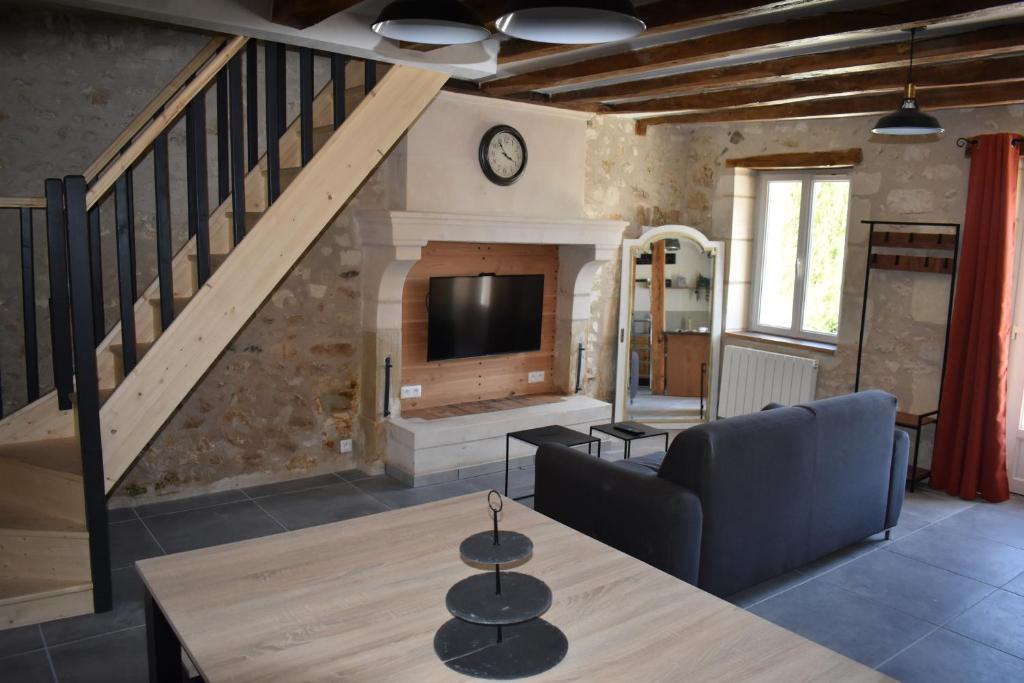 a living room with a couch and a tv at Maison de charme in Ligueil