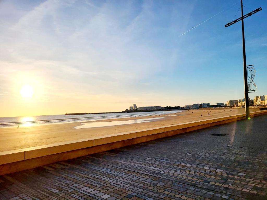 vistas a una playa con puesta de sol en el fondo en Sur le remblai des Sables comprenant 2 ch parking et piscine, en Les Sables-dʼOlonne