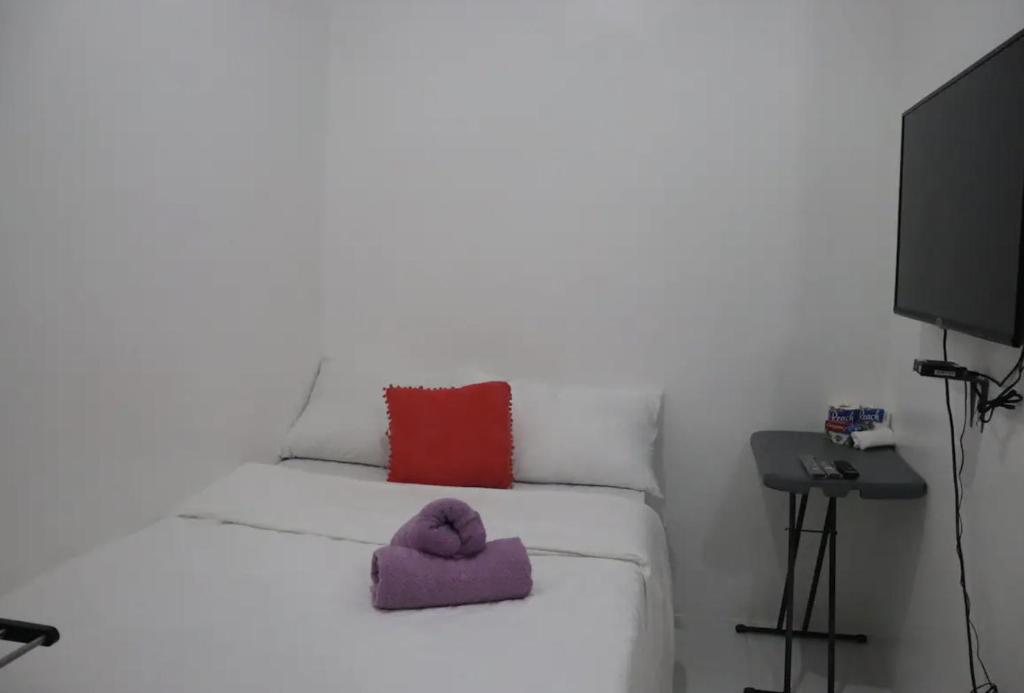 a white bed with a purple towel on it at PORTSIDE STUDIOS in Manila