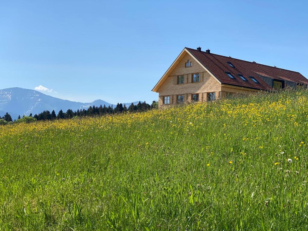 uma casa numa colina num campo de relva em Gähwindehof Mountain Ranch Resort em Oberstaufen