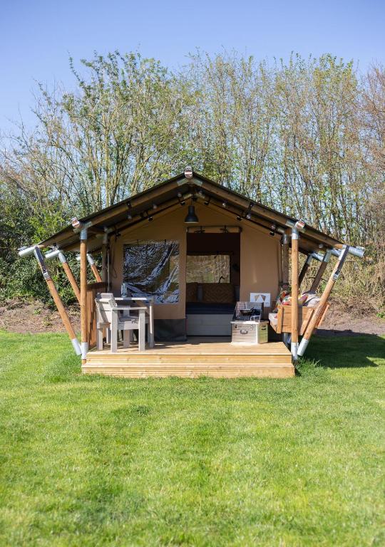 a gazebo with a table and chairs in the grass at Safaritent Lodge 2 plus in Ruurlo