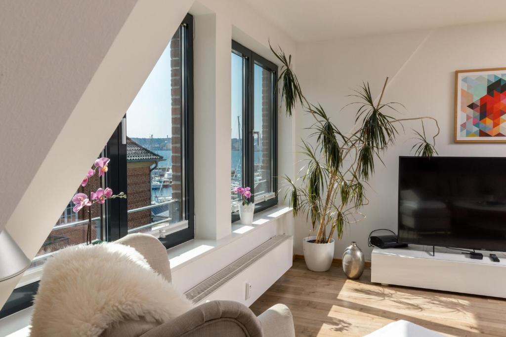 ein Wohnzimmer mit großen Fenstern und einem Flachbild-TV in der Unterkunft Ferienwohnung Seestern in Flensburg, Sonwik in Flensburg
