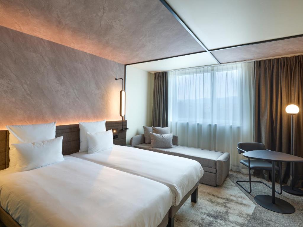 een hotelkamer met 2 bedden en een tafel bij Novotel Bern Expo in Bern