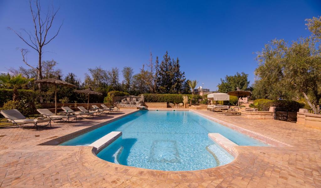 een groot zwembad met ligstoelen bij Villa Ferme de Coco in El Caïd Omar