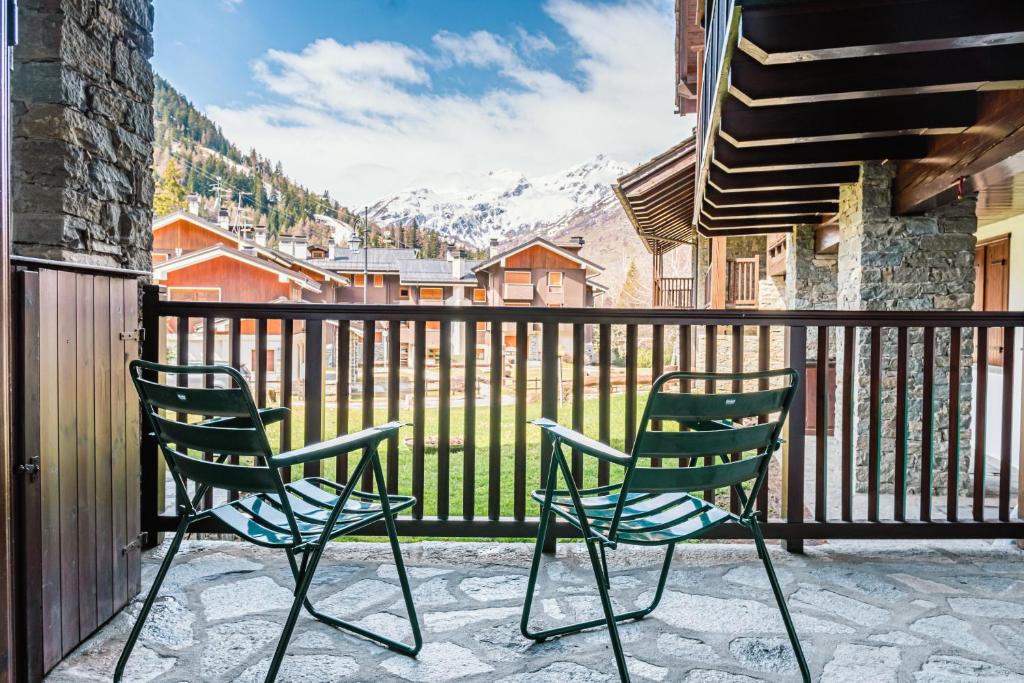twee stoelen op een balkon met bergen op de achtergrond bij [Aosta - La Thuile] - Condominio Rolland in La Thuile