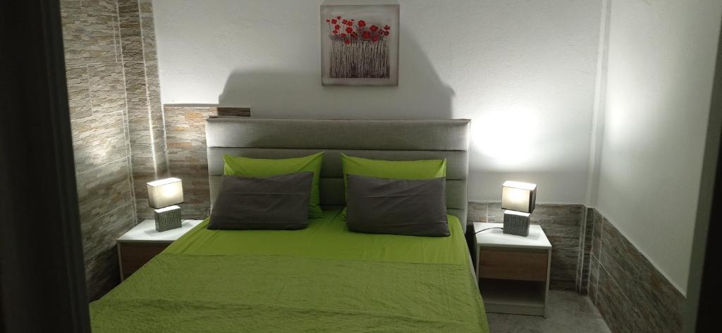 ein Schlafzimmer mit einem grünen Bett mit zwei Lampen in der Unterkunft Angel Room 1 in Nea Plagia